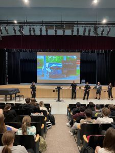 police officers in front of a screen in an auditorium full of kids