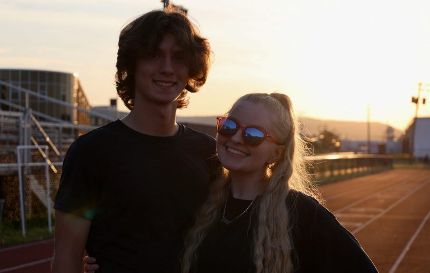 two students in front of a sunset