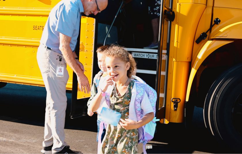 student smiling getting off of the bus