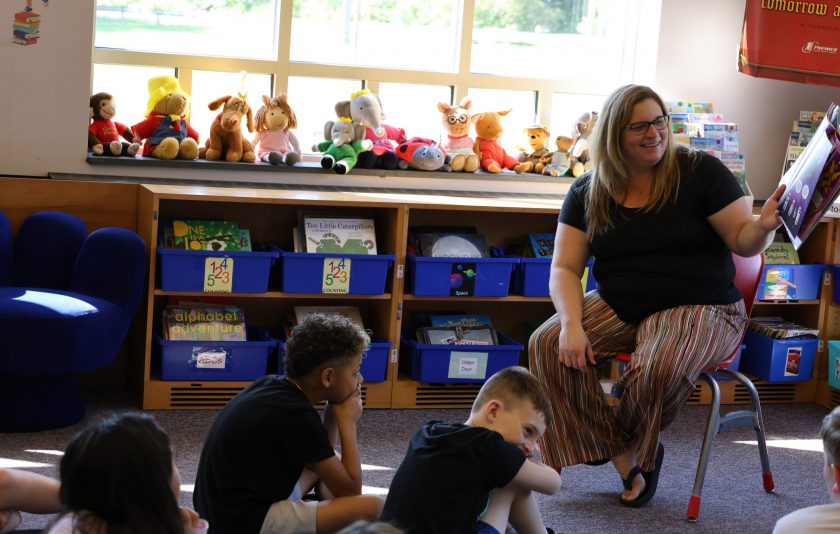 librarian reading book to students sitting on floor