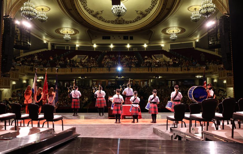 students wearing kilts on stage in dramatic lighting at Proctors Theatre