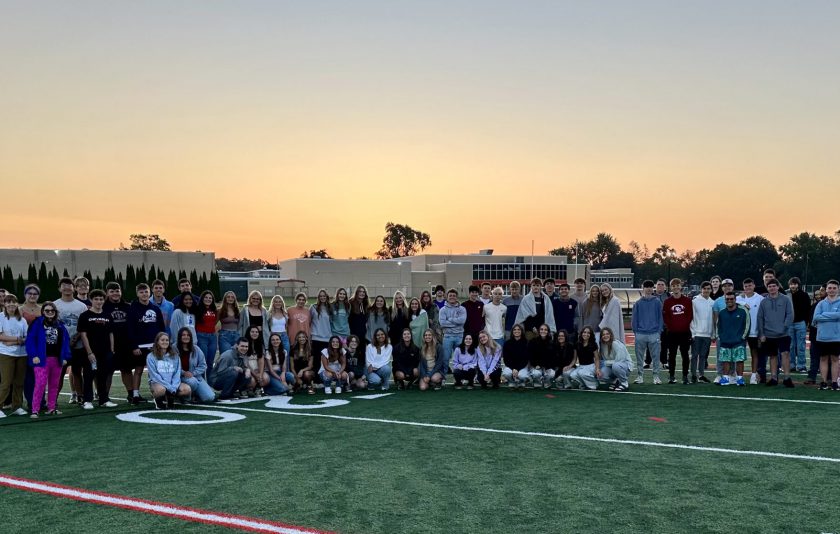 senior students on football field with sunrise behind them