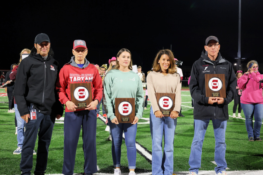 Athletic Director and four adults holding their hall of fame plaques on the football field with the school band behind them