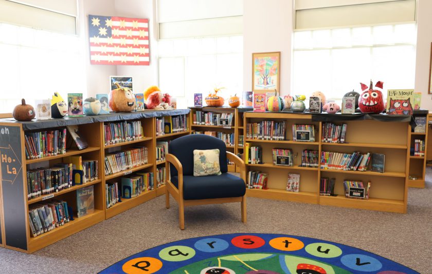 bookshelves woth decorated pumpkins next to books with an american flag in the back