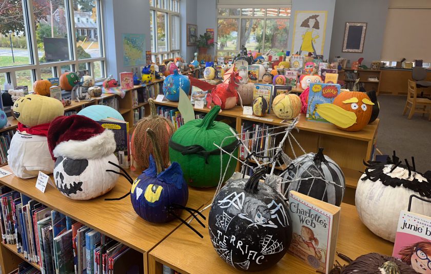 book character pumpkins on top of library bookshevles