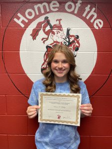 student with long wavy hair holds certificate and smiles