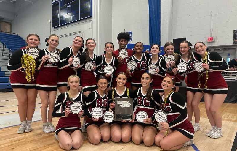 some cheerleaders sitting down with others standing behind them holding plaques