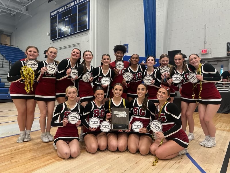 some cheerleaders sitting down with others standing behind them holding plaques