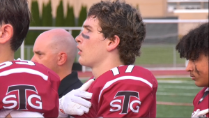 football player with hand on heart singing National Anthem