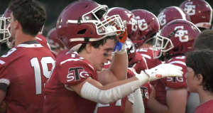 football player pulls helmet up to talk to brother