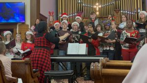 singers, some dressed in red christmas hats, performing at a church