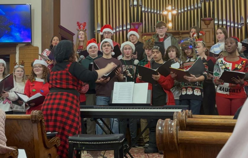 singers, some dressed in red christmas hats, performing at a church