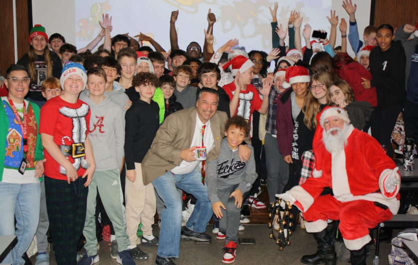 santa claus crouched down with students and the principal and assistant principal