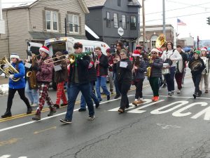 pep band marching down street playing instruments in holiday attire