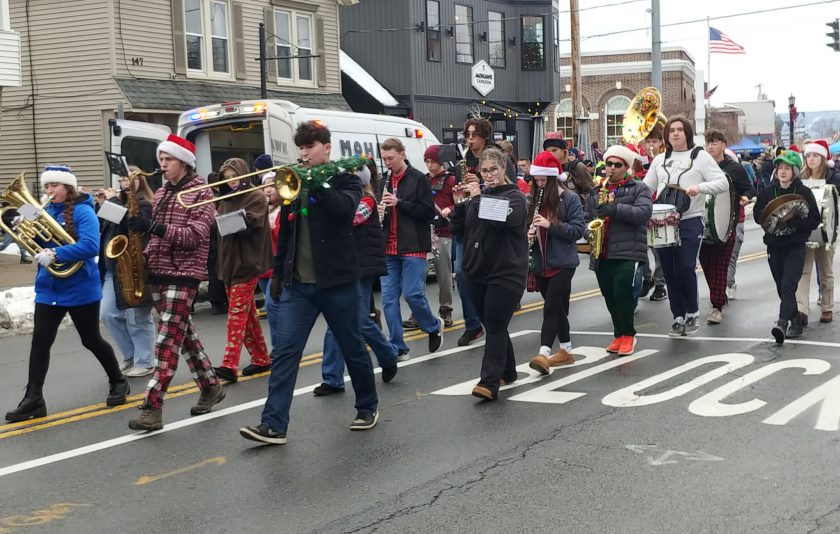 pep band marching down street playing instruments in holiday attire