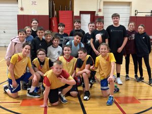 sixth grade students smiling together on the basketball court 