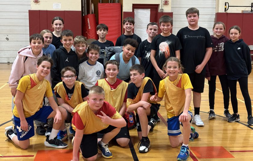 sixth grade students smiling together on the basketball court