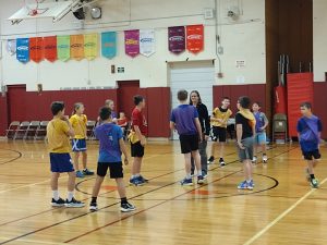 students in yellow and other students in blue before the jump shot on the basketball court