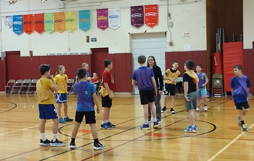 students in yellow and other students in blue before the jump shot on the basketball court