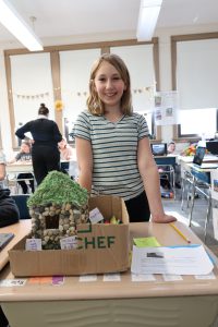 student standing behind a stone Inca house she created