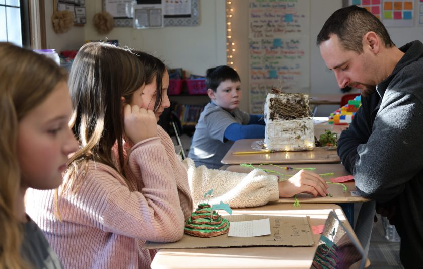 teacher looks at Inca projects students made on their desks