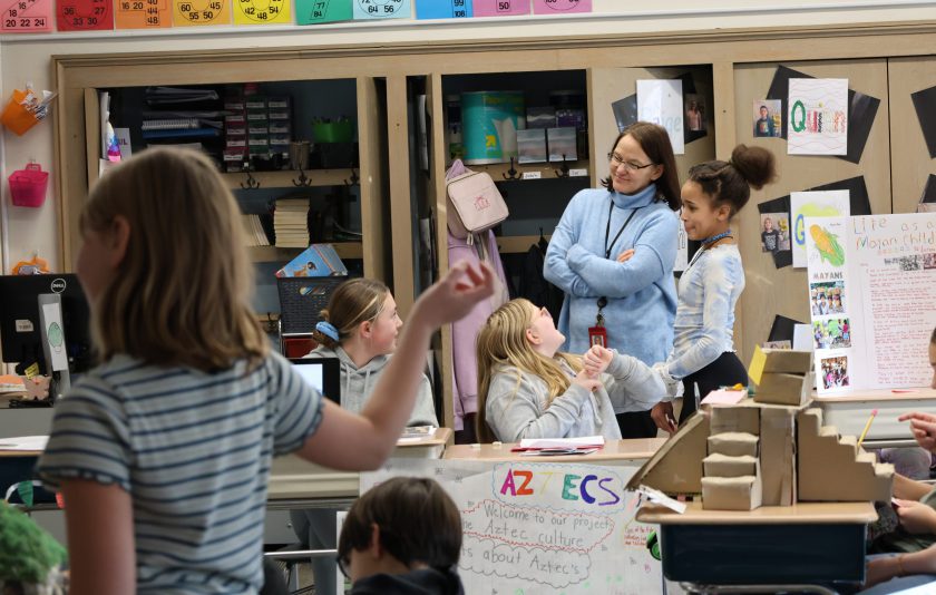 student leans over to student while others are laughing