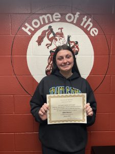 student smiles holding certificate of achievement