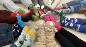 students sitting on the floor in a circle with their feet together and colorful and fun socks as the focal point