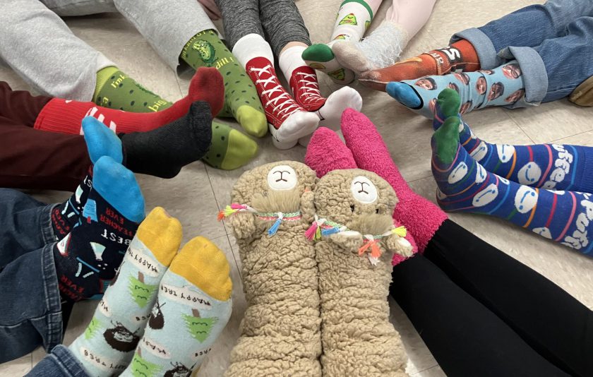 students sitting on the floor in a circle with their feet together and colorful and fun socks as the focal point