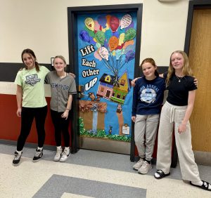 four students standing beside a door they decorated 